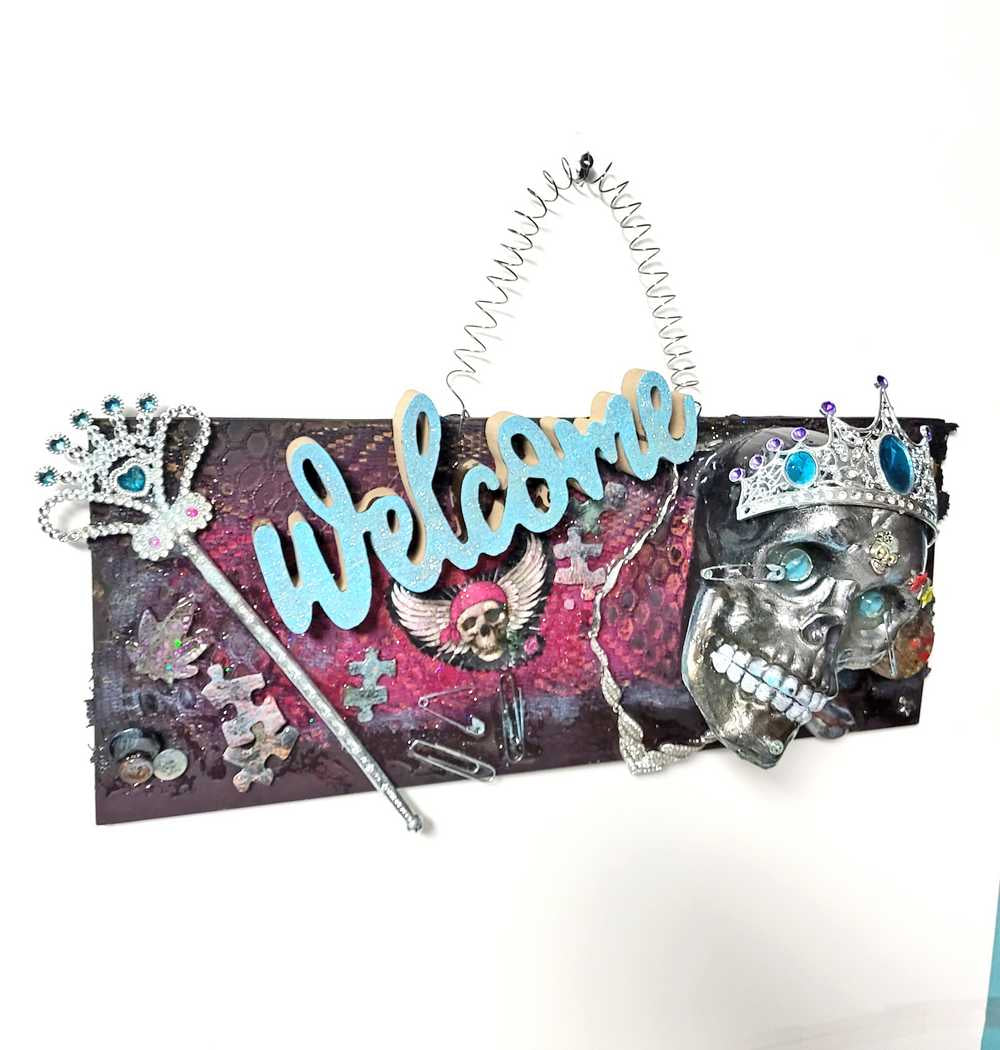 Welcome Sign With a Silver Colored Skull With Piercings Wearing a Crown And Her Scepter