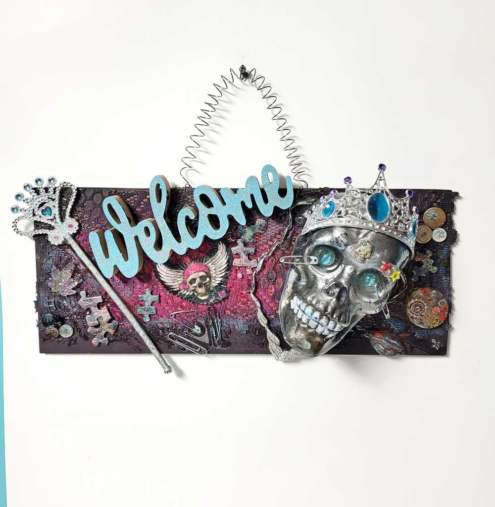 Welcome Sign With a Silver Colored Skull With Piercings Wearing a Crown And Her Scepter