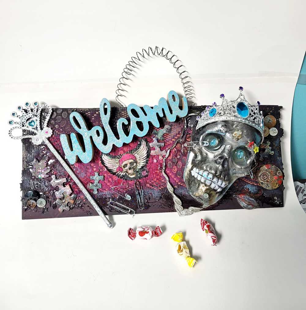 Welcome Sign With a Silver Colored Skull With  Piercings Wearing a Crown And Her Scepter