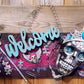 Welcome Sign With a Silver Colored Skull With  Piercings Wearing a Crown And Her Scepter