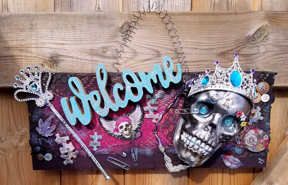 Welcome Sign With a Silver Colored Skull With  Piercings Wearing a Crown And Her Scepter