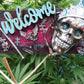 Welcome Sign With a Silver Colored Skull With  Piercings Wearing a Crown And Her Scepter