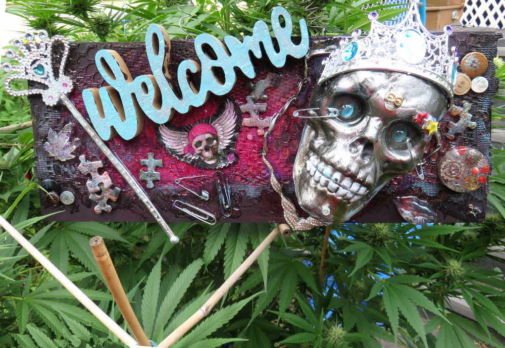 Welcome Sign With a Silver Colored Skull With  Piercings Wearing a Crown And Her Scepter