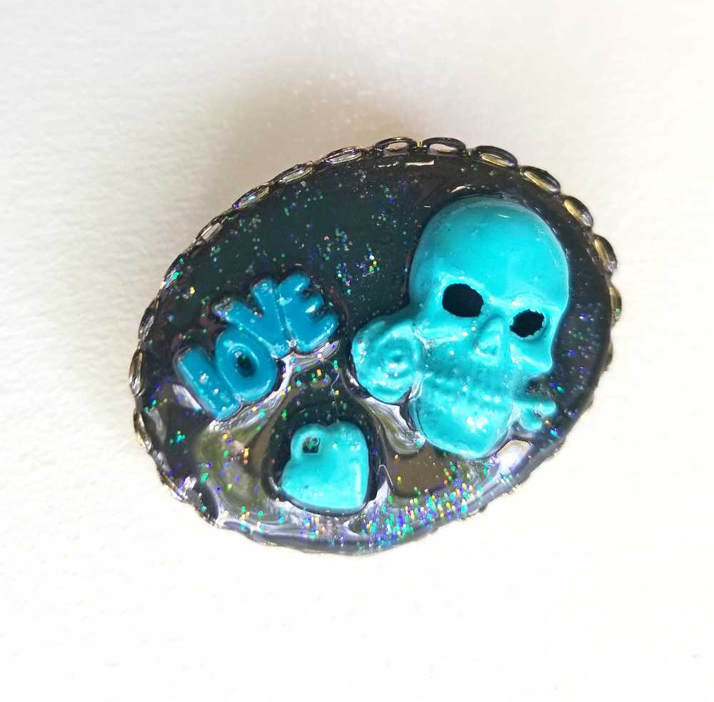 Porcelain Black Oval Shaped Brooch with Hand Painted Teal Skull, Heart & Love Charms