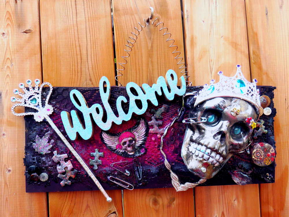 Welcome Sign With a Silver Colored Skull With  Piercings Wearing a Crown And Her Scepter