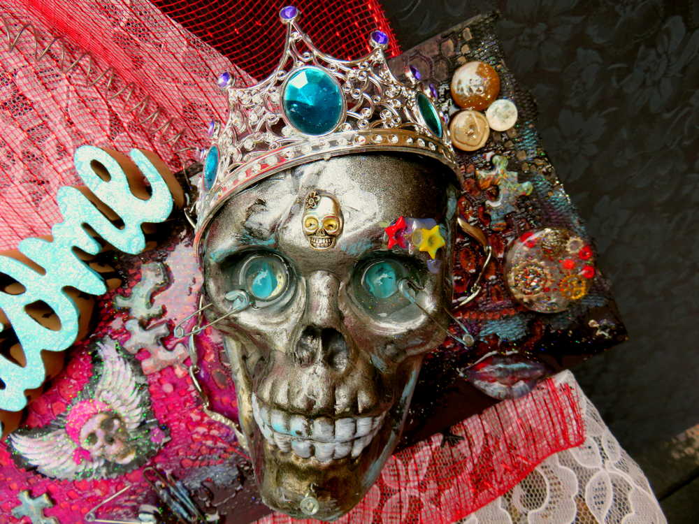 Welcome Sign With a Silver Colored Skull With  Piercings Wearing a Crown And Her Scepter