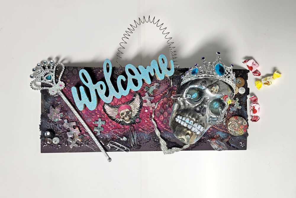 Welcome Sign With a Silver Colored Skull With  Piercings Wearing a Crown And Her Scepter