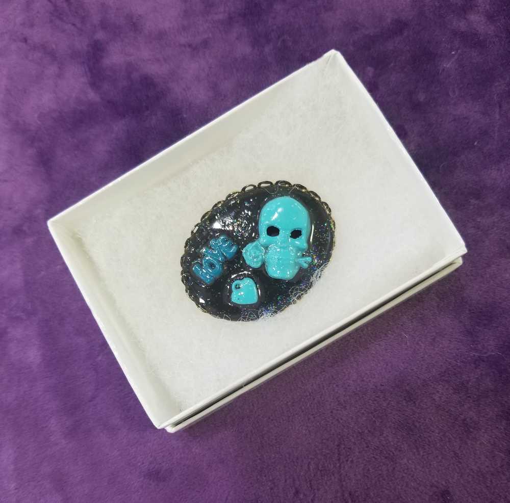 Porcelain Black Oval Shaped Brooch with Hand Painted Teal Skull, Heart & Love Charms