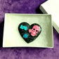 Black Porcelain Heart Shaped Brooch with a Pink Skull and a Teal Heart & Love Charm