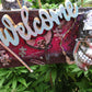 Welcome Sign With a Silver Colored Skull With  Piercings Wearing a Crown And Her Scepter