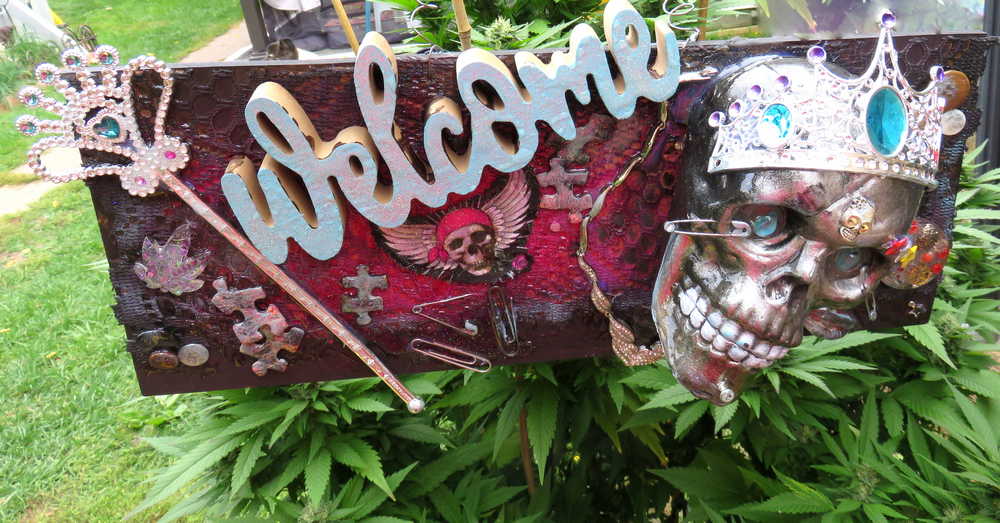 Welcome Sign With a Silver Colored Skull With  Piercings Wearing a Crown And Her Scepter