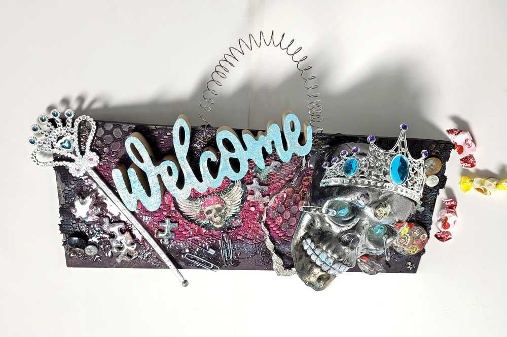 Welcome Sign With a Silver Colored Skull With  Piercings Wearing a Crown And Her Scepter