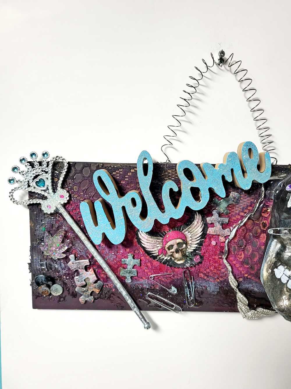 Welcome Sign With a Silver Colored Skull With  Piercings Wearing a Crown And Her Scepter